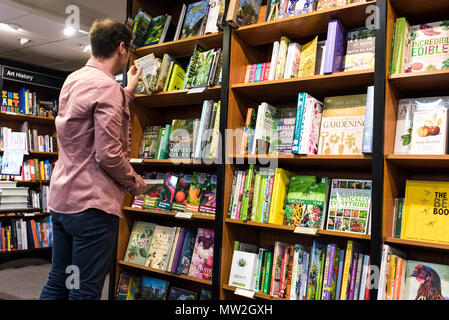 Client à la recherche de livres dans une librairie Waterstones. Banque D'Images