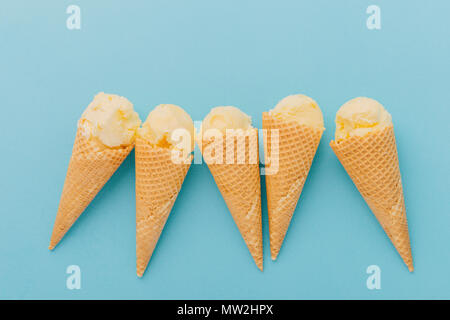 Cinq délicieuses glaces en cônes alvéolés sur fond bleu Banque D'Images