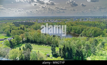 Vue aérienne d'un petit lac au milieu de la forêt derrière les installations industrielles de la ville, drone abattu Banque D'Images