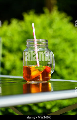 Un verre de pimms dans un pot de confiture avec un papier de verre à l'extérieur de paille sur un jour d'été. Banque D'Images