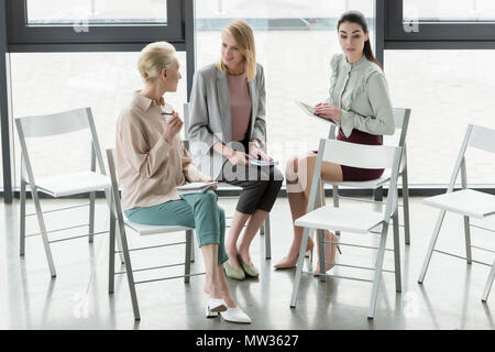 Les femmes d'affaires professionnel assis sur des chaises et talking in office Banque D'Images