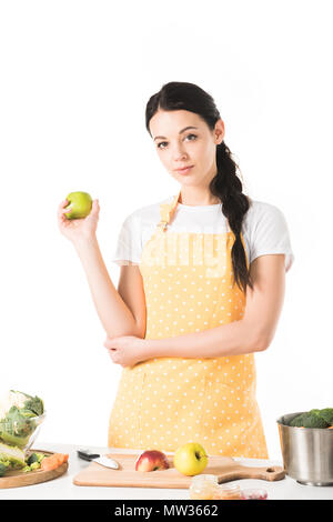 Woman holding apple près de table avec planche à découper, casserole, les pommes et les légumes Banque D'Images