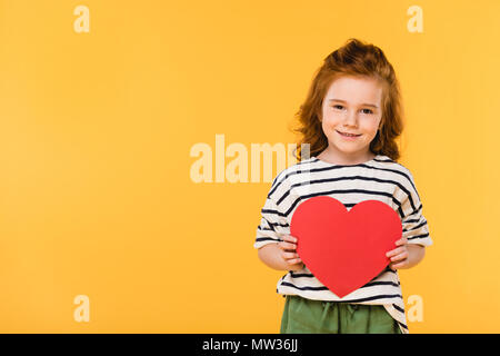 Portrait of smiling kid avec papier rouge coeur isolé sur fond jaune, st valentines day concept Banque D'Images