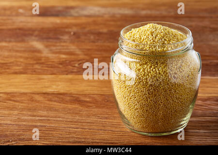 Matières naturelles bio millet dans un bocal en verre sur une table en bois, horizontal, copy space, close-up. Certains copie espace pour votre inscription. Protéines organiques. Nu Banque D'Images