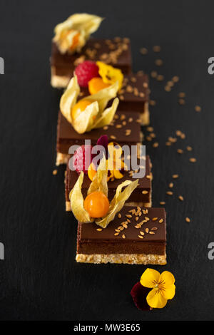 Gâteau au chocolat végétalien premières décorées avec des physalis, framboises et fleurs sur fond noir Banque D'Images