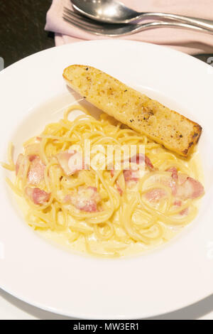 Spaghetti carbonara pâtes nouilles au jambon fromage et bacon sur pain plat blanc à l'heure du dîner Banque D'Images