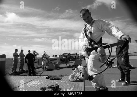 Airman Senior Charles Burkhardt, 9e Escadron de génie civil et de l'eau alimente l'entretien des systèmes, l'équipement de protection personnelle dons avant qu'il entre dans un espace clos pendant un exercice à Beale Air Force Base, en Californie, le 27 avril 2017. Les EPI d'entrée dans un espace clos peut inclure un full body suits, harnais de sécurité, des bottes en caoutchouc, des gants, des bouteilles d'oxygène et des masques à gaz. Banque D'Images