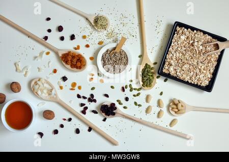 Concept de cuillères en bois plein de graines, de céréales et de miel sur fond blanc, table top Banque D'Images