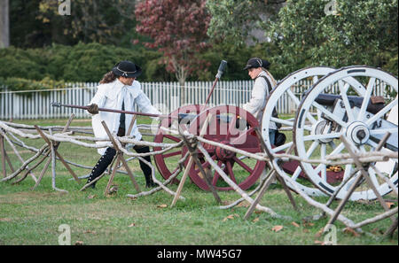 Deux colonials chargement d'un canon à roues rouge pour le tir à la fin de la journée au centre historique Colonial Williamsburg. Banque D'Images