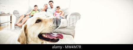 Happy Family sitting on couch avec leur animal de labrador jaune en premier plan Banque D'Images