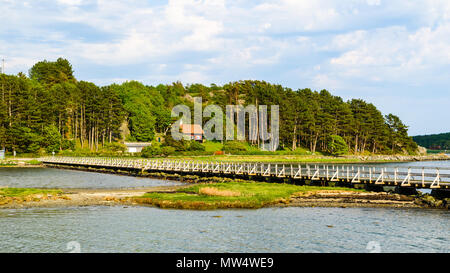 Joli paysage côtier avec une longue passerelle au-dessus de l'eau peu profonde et une maison dans les arbres en arrière-plan. Arod près de Kungalv, Suède. Banque D'Images