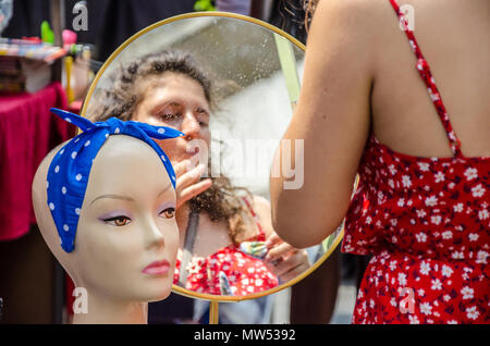 Un jeune adulte se regarde dans un miroir sur un étal de marché. Banque D'Images