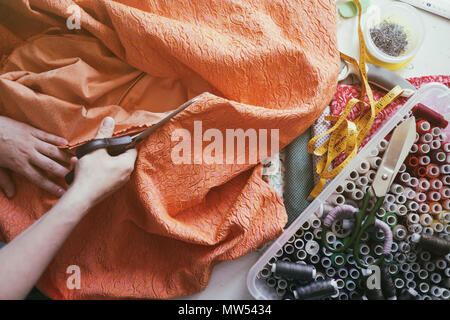 Woman cutting tissu orange Banque D'Images