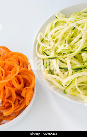 Renforts spiralés de carottes et courgettes sur plaques avec fond blanc. Banque D'Images