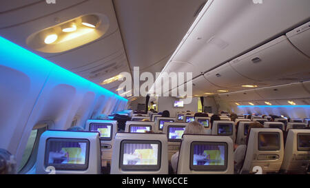 Avion passagers intérieur avec les gens sur place. Cabine de l'avion avec des rangées de sièges. Les passagers qui voyagent par un avion commercial moderne, à l'intérieur d'un avion. Concept de voyage. Banque D'Images