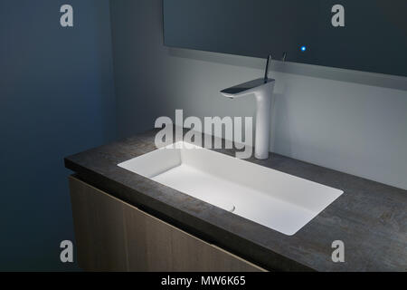 L'intérieur minimaliste d'une salle de bains moderne avec lavabo et miroir en médaillon blanc Banque D'Images