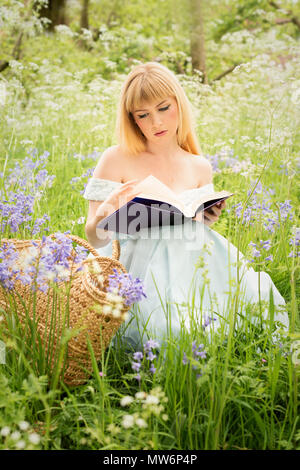 Femme assise au printemps meadow la lecture d'un livre Banque D'Images