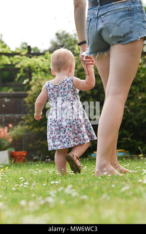 Belle Jeune fille bébé enfant à 18 mois avec des cheveux blonds courts walking in garden - modèle publié photographie prise par Simon Dack Banque D'Images