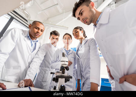 Groupe des travailleurs médicaux debout dans un cercle sur le tableau avec microscope Banque D'Images