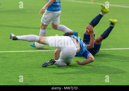 Les joueurs de football tumbling sur le terrain de football. Les joueurs tombent dans la lutte pour le ballon. Banque D'Images