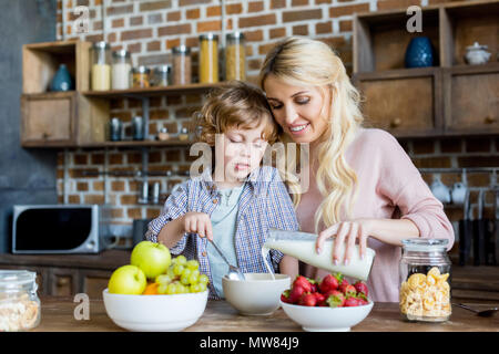 Heureuse mère et petit fils de verser dans un bol de lait pour le petit déjeuner Banque D'Images