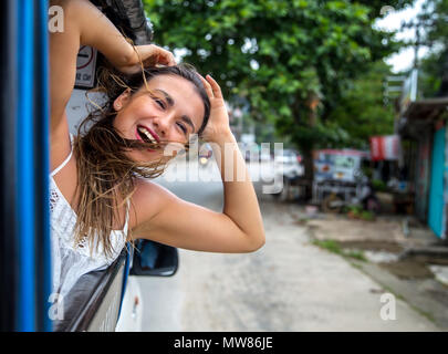 Smiling girl regarde par la fenêtre d'un taxi, tuk-tuk travel concept Banque D'Images