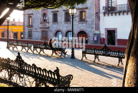 Un jeune couple assis sur un banc en métal dans la région de jardin (le jardin) dans le centre de San Miguel de Allende, Mexique Banque D'Images