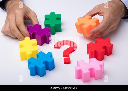 Main humaine Problèmes Puzzle multicolore avec signe d'interrogation sur fond blanc Banque D'Images