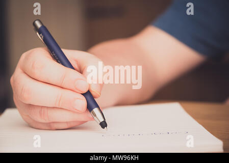 La main de l'homme écrit sur un bloc-notes avec un stylo, concept copywriting Banque D'Images