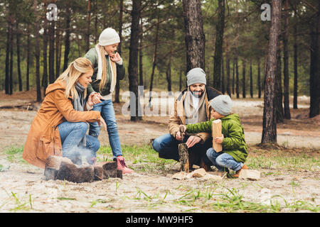 Famille heureuse faisant feu de camp tout en ayant voyage sur jour d'automne Banque D'Images