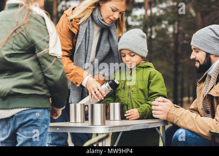 Belle jeune mère pouring tea de thermos pour les enfants on camping trip Banque D'Images