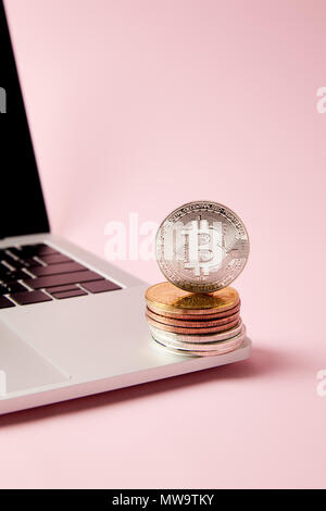 Close-up shot de bitcoins empilés sur un ordinateur portable sur la surface rose Banque D'Images