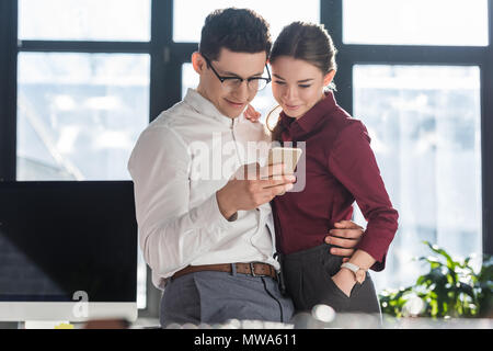 Jeunes gens d'avoir des vêtements formels et à l'aide d'office romance ensemble smartphone Banque D'Images