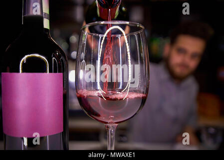 Bouteille et un verre de vin rouge sur la barre.vin rouge verse de la bouteille dans le verre de vin. Banque D'Images