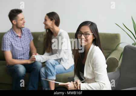 Portrait of smiling asian conseiller avec happy couple at background Banque D'Images