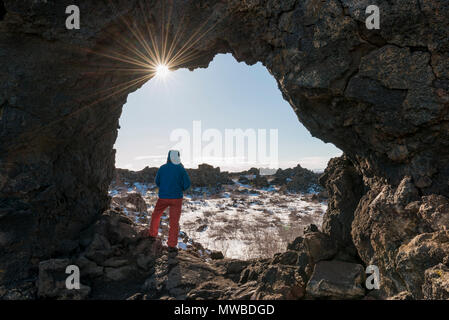 L'homme dans un rock arch, soleil, paysage volcanique de Krafla, zone volcanique, Dimmuborgir, Parc National de Mývatn, Islande Banque D'Images