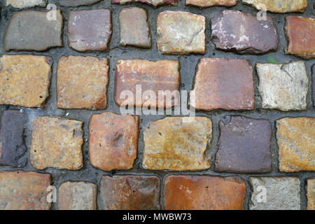 Chaussée de pierre, pierres de couleur marron et jaune de forme carrée, fond de pavés. Banque D'Images
