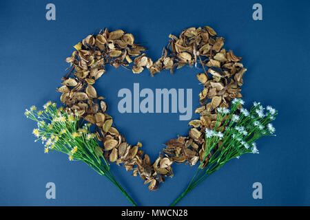Pétales secs en forme de coeur sur fond bleu. Banque D'Images