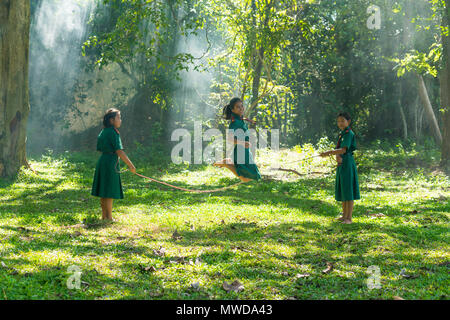 ., Thaïlande - 31 juillet 2016 : trois jeunes filles en uniforme d'jouer jeu de saut ensemble sur terrain dans les régions rurales de la Thaïlande,. Banque D'Images