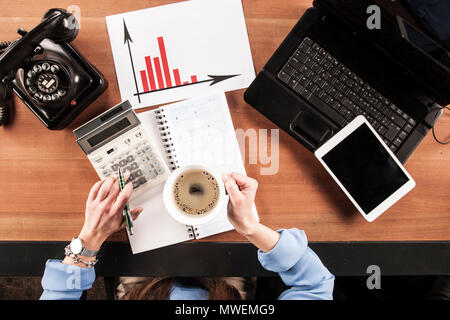 S'occupe des formalités administratives secrétaire au bureau, café en main et calculatrice, vue d'en haut Banque D'Images