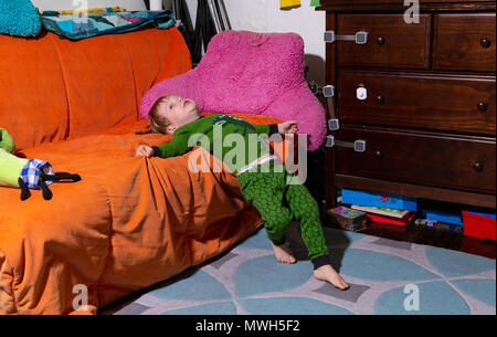 Caucasian Toddler jette sur son canapé dans sa chambre avant d'aller au lit Banque D'Images