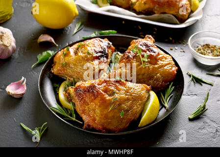 Haut de cuisses de poulet sur la plaque sur la table en pierre noire Banque D'Images