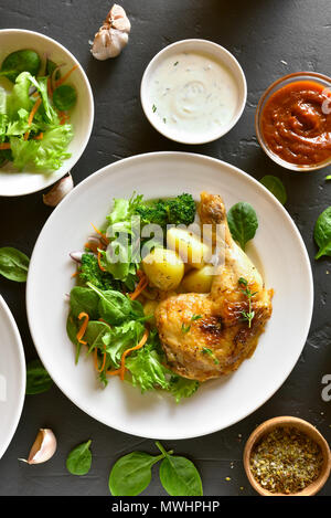 Cuisse de poulet frit avec des pommes de terre et salade verte sur fond noir en noir. Haut de la vue, télévision lay Banque D'Images