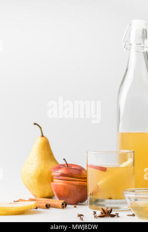 Cidre en bouteille avec le verre et fruits sur surface blanche Banque D'Images