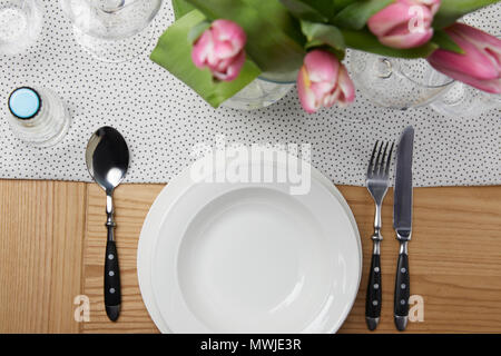 De la vaisselle avec des assiettes sur la table avec des fleurs dans un vase Banque D'Images