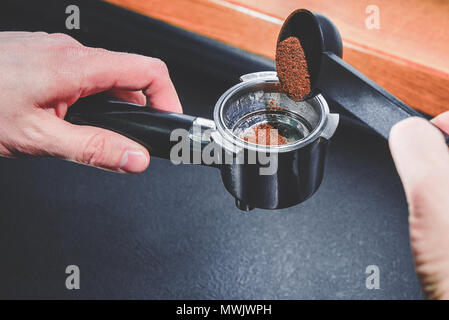 La préparation du café. L'homme est titulaire d'une rectifieuse de café dans sa main et la remplit de café moulu. Temps de faire une pause, le temps pour le café. Café noir, Banque D'Images