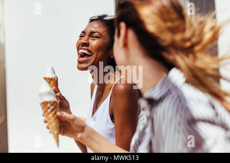 Deux heureux à la women eating ice cream cones sur une journée ensoleillée à l'extérieur. Banque D'Images
