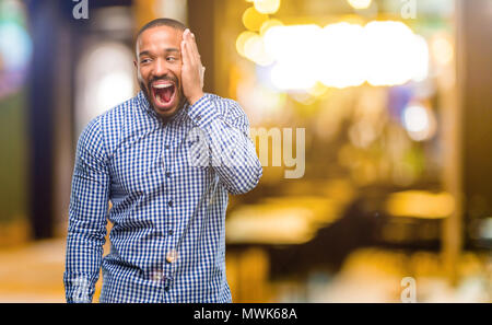 African American man with beard si heureux et confiant montrant un grand sourire surpris collés dans la nuit Banque D'Images