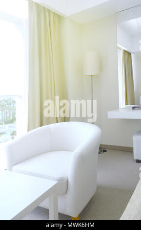 Fragment de la chambre de l'hôtel. Une table, un fauteuil et une lampe de plancher dans le coin de la chambre d'hôtel Banque D'Images