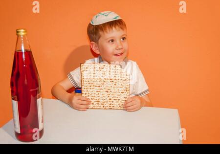 Peu caucasien enfant avec une kippa sur la tête de manger la matsa. La Pâque juive illustration. Banque D'Images